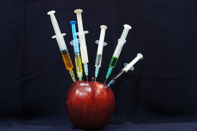 Roter Apfel, in dem viele Spritzen stecken - WHO Pandemievertrag